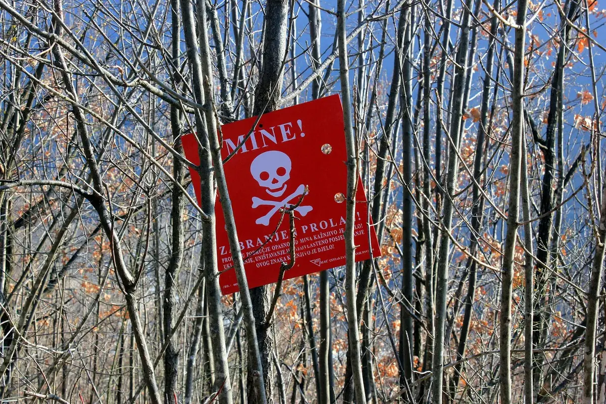 Red mine warning sign with a skull in woods east of Sarajevo, reading MINE! ZABRANJEN PROLAZ