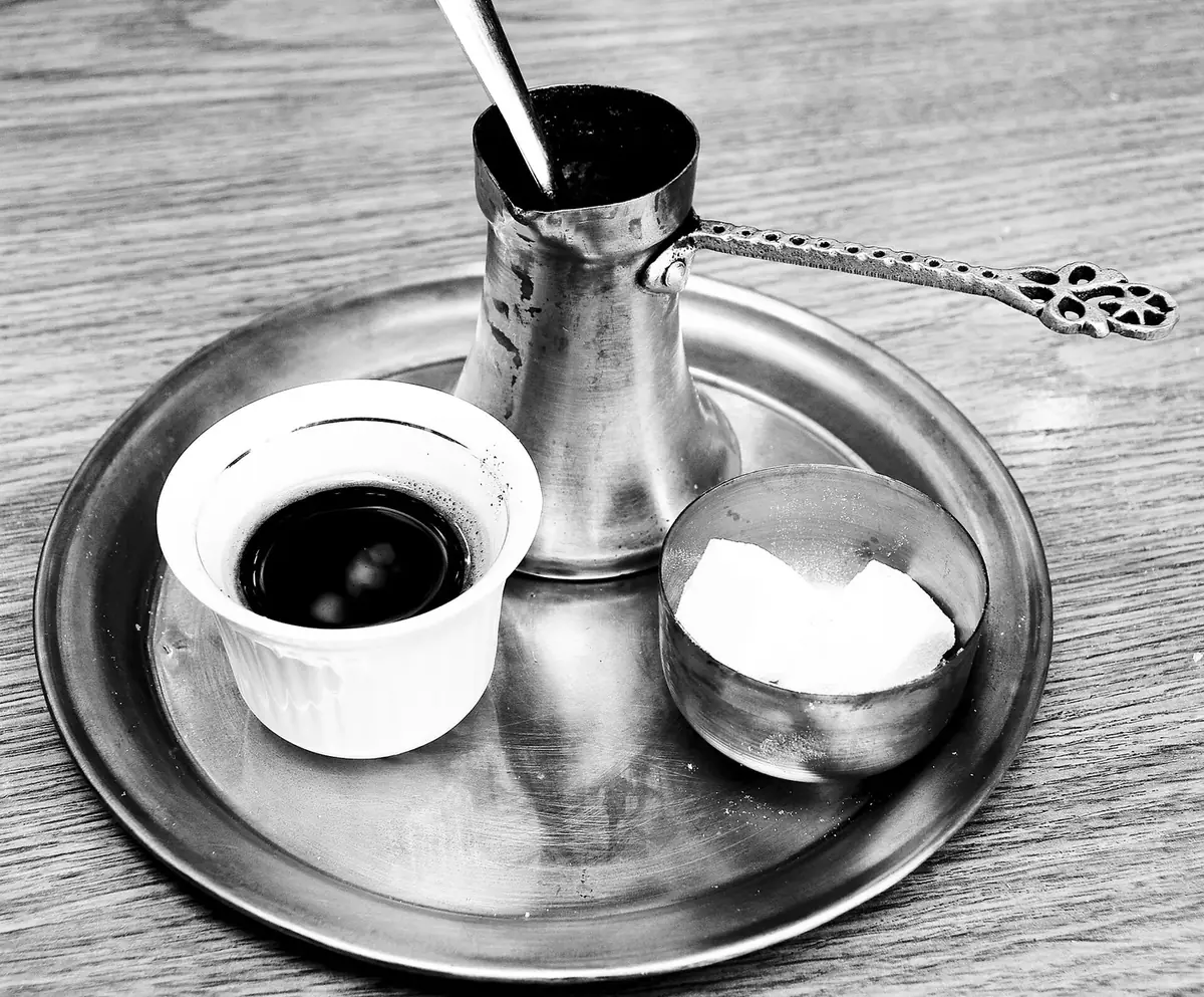 Bosnian coffee set in Sarajevo: a džezva, a small cup of coffee and a bowl of sugar cubes on a metal tray