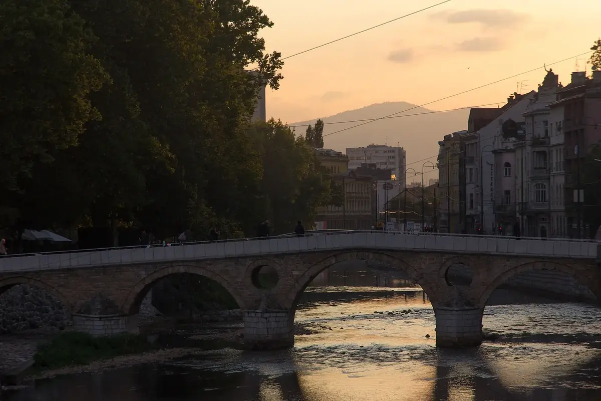 The Latin Bridge in Sarajevo at sunset, a low stone bridge over the Miljacka river