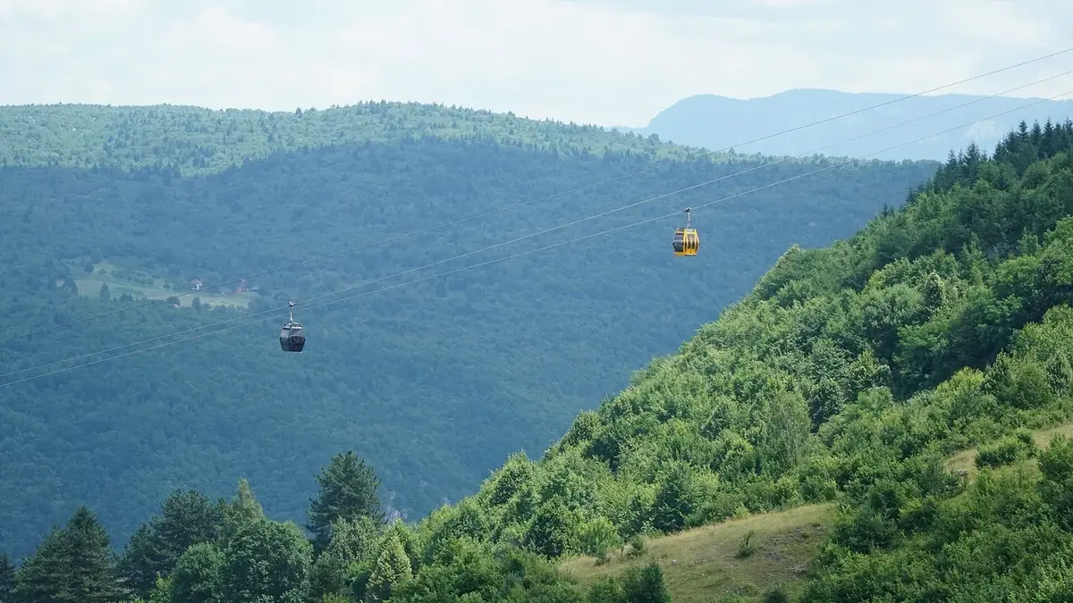 Two cable car cabins on the Trebević cable car above green forest near Sarajevo