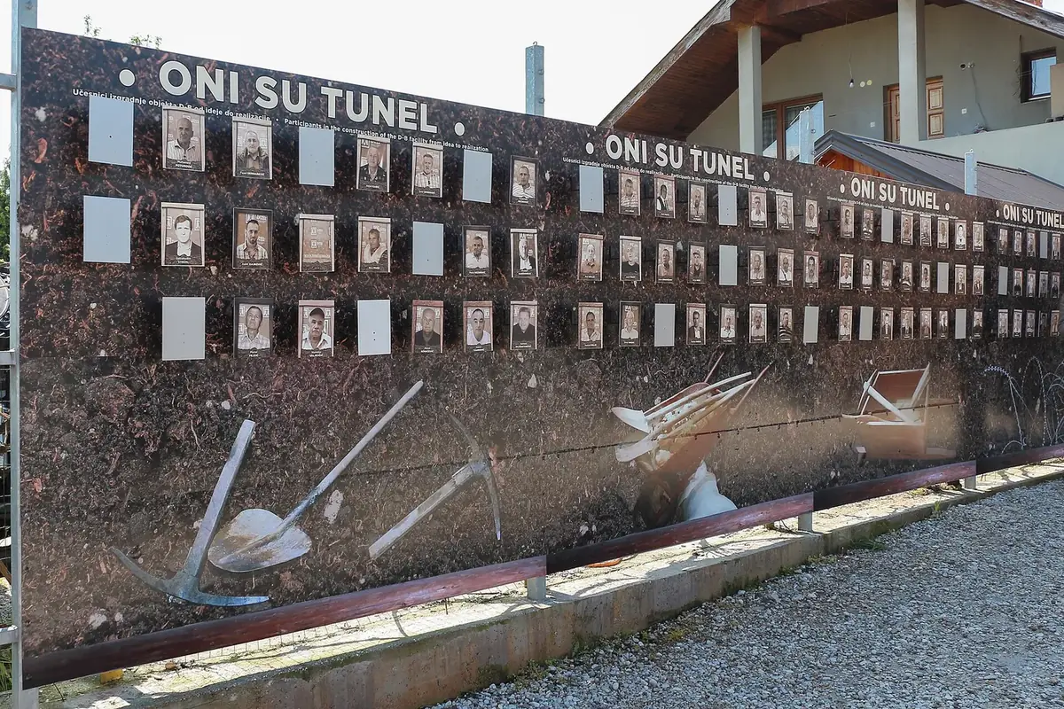 A long outdoor wall at the Tunnel of Hope with portraits of the people who built the tunnel, titled Oni su tunel