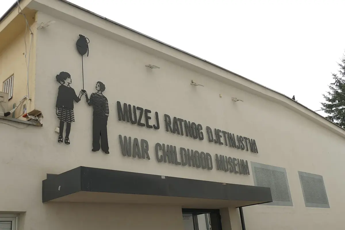The front of the War Childhood Museum in Sarajevo, with the sign Muzej ratnog djetinjstva and cut-out figures of two children holding a balloon