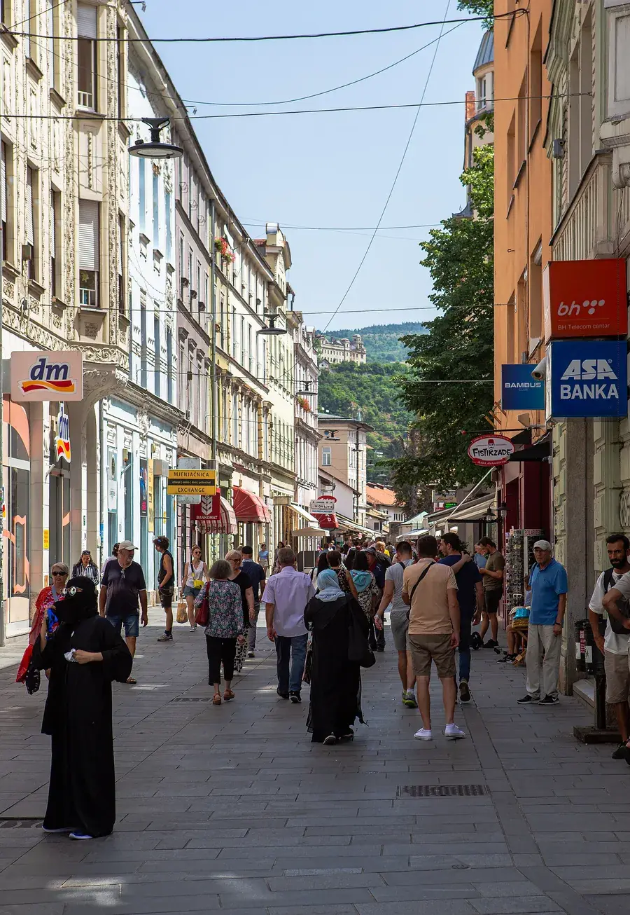 People walking down Ferhadija, a paved street of old Austro-Hungarian buildings in central Sarajevo