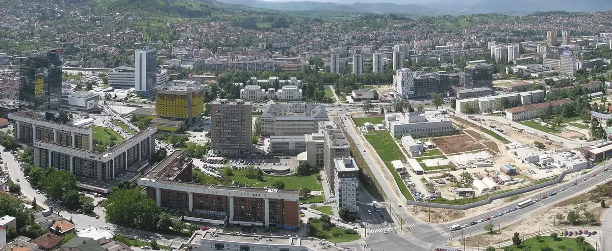 Marijin Dvor in Sarajevo seen from above, with office towers, government buildings and green hills behind