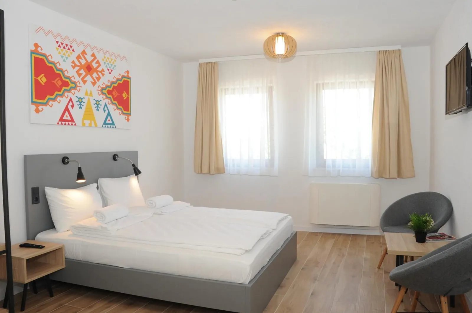 The queen bed under the red kilim print, with two chairs and a TV