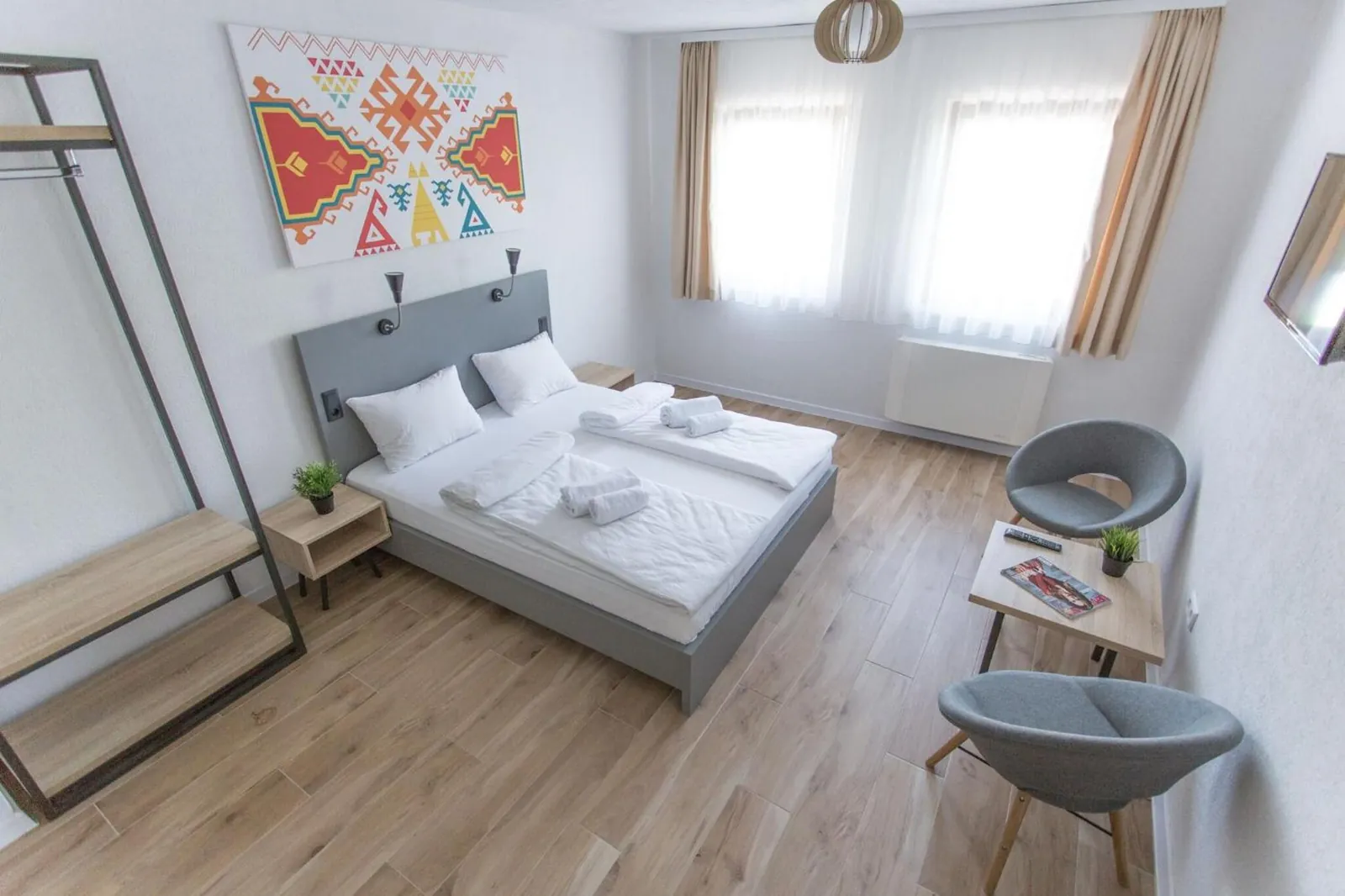The room with its clothes rack, two chairs and the kilim print