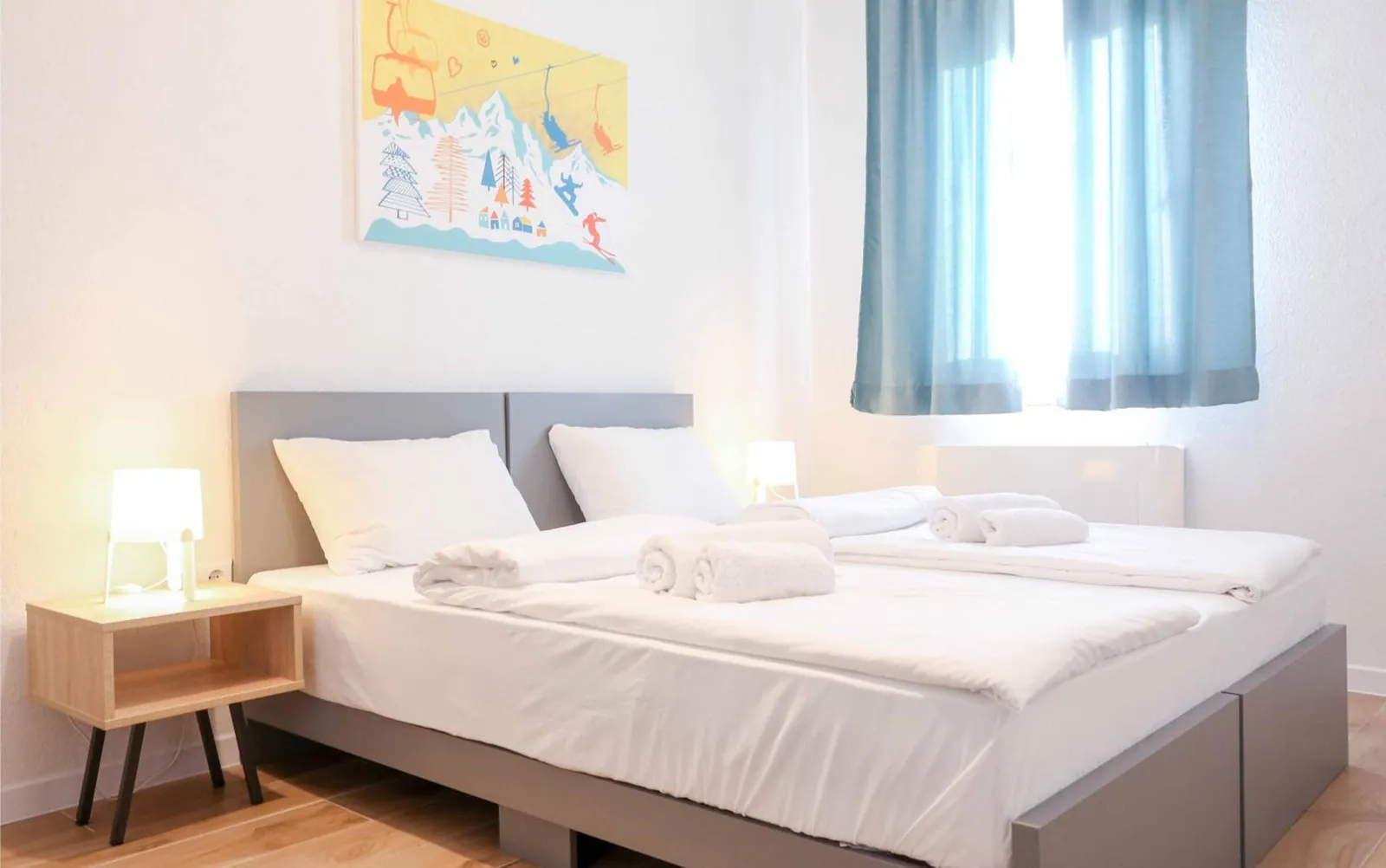 Two beds pushed together under the mountain print, by the window