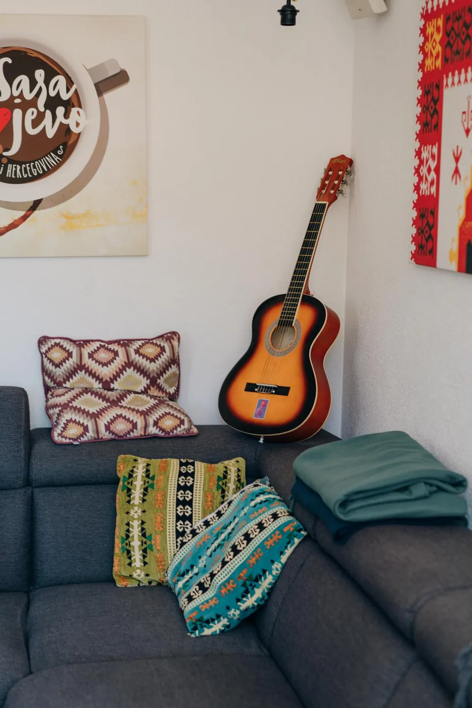 A sofa with bright cushions and a guitar in our lounge