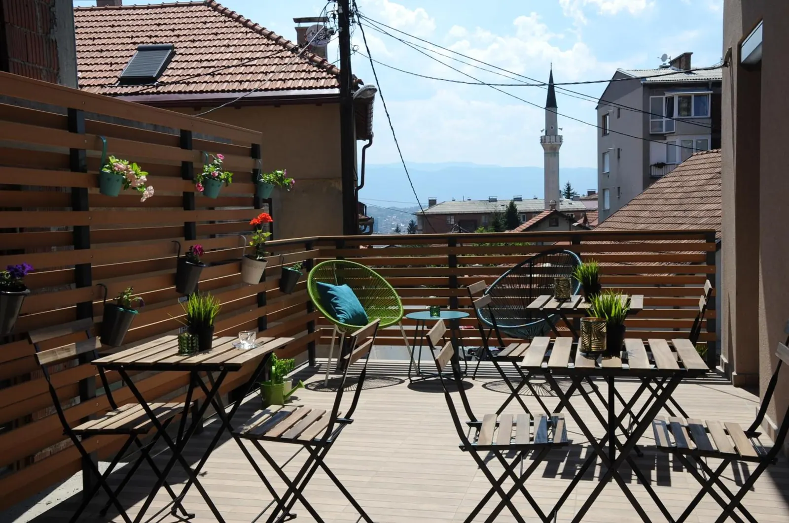 The terrace, with tables and a view over the roofs to a minaret and the hills