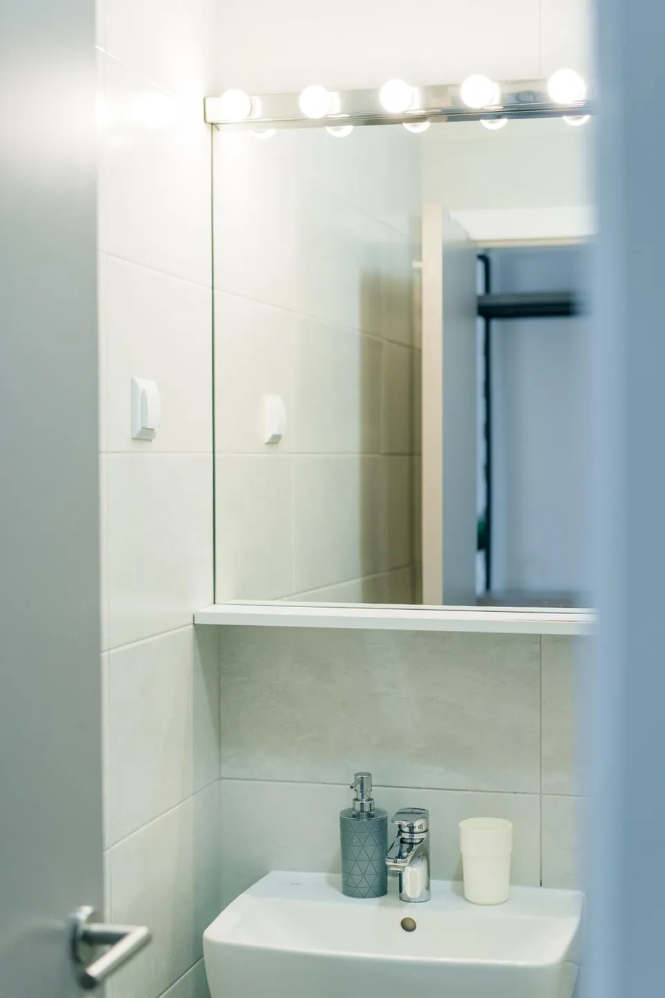 A clean bathroom with a big lit mirror