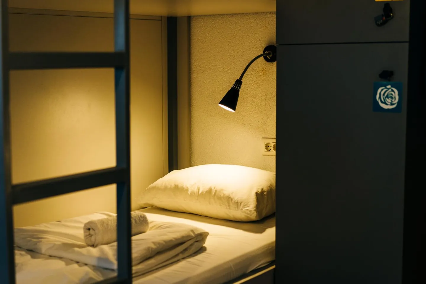 A made-up bunk with its own reading light and a locker